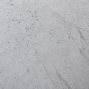 Polished Carrara marble slab with cool white background and fine grey veining on a black display stand