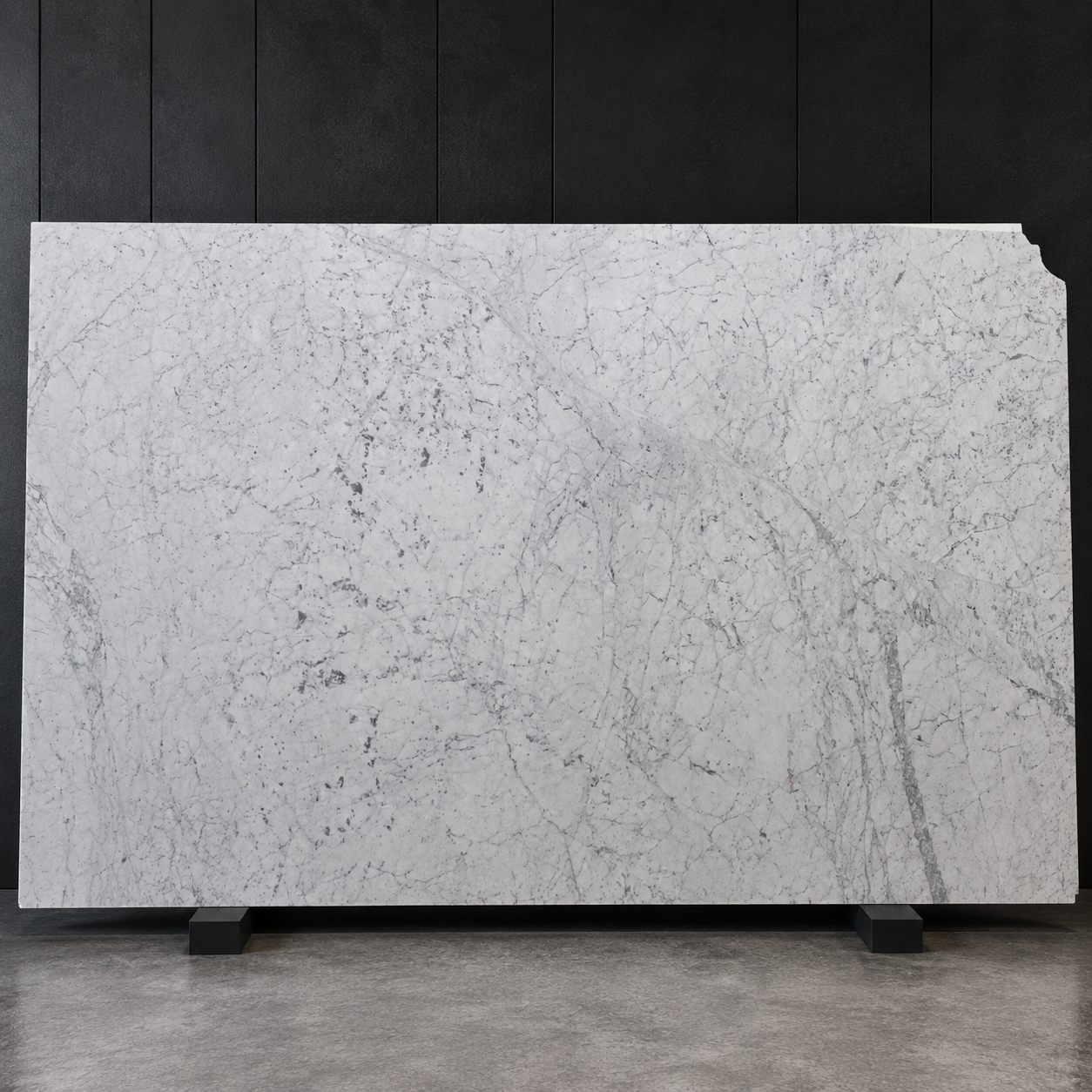 Polished Carrara marble slab with cool white background and fine grey veining on a black display stand