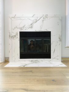 White Carrara marble fireplace surround and hearth with a black firebox