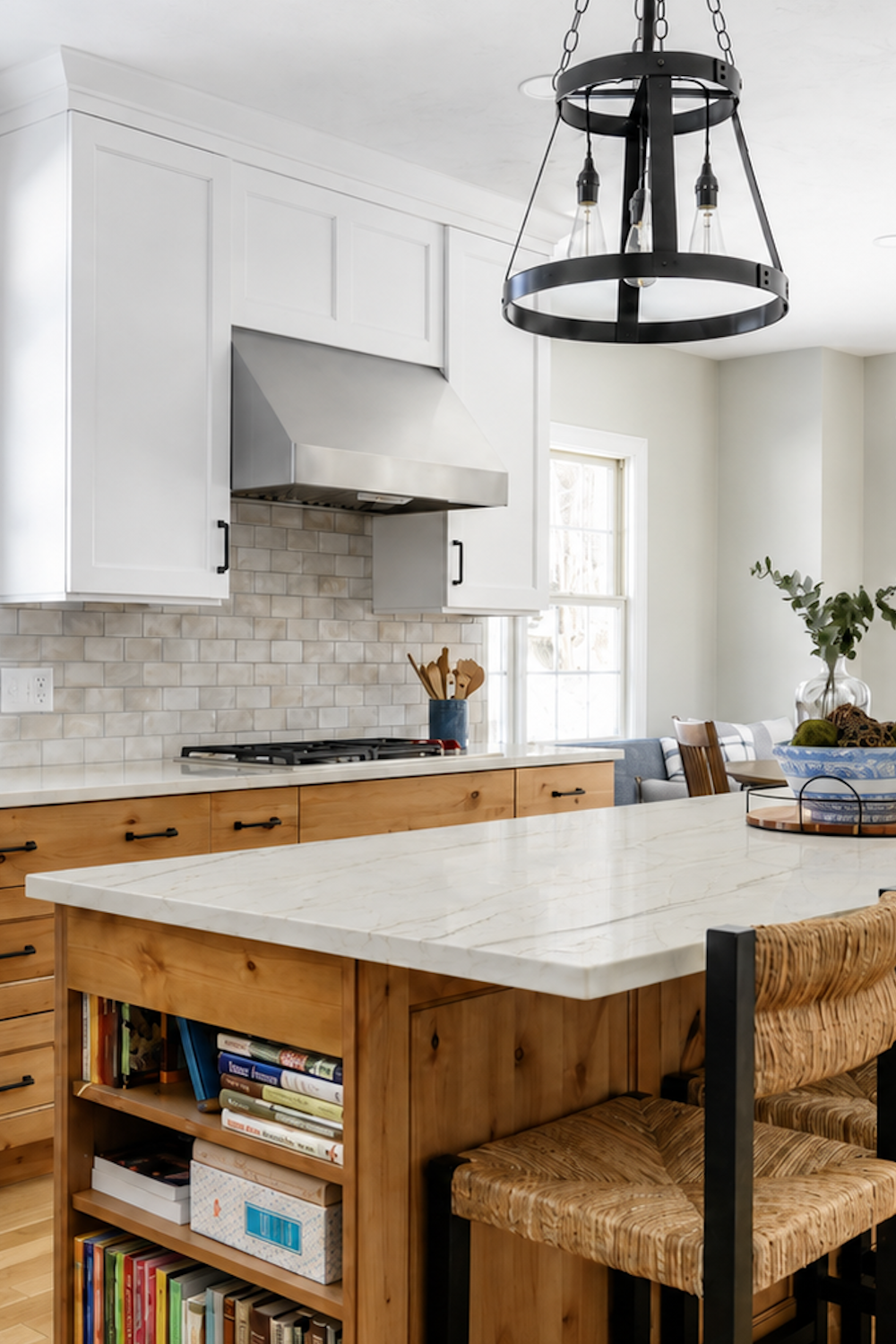 White Bianco Superiore quartzite island with gold veining, knotty pine cabinets and a black iron chandelier